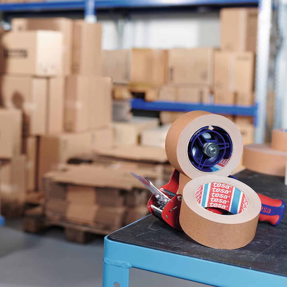 tesa 4713 Papier-Packband in Handabroller – Nahaufnahme beim Abziehen des umweltfreundlichen Klebebands für effiziente Kartonverpackung